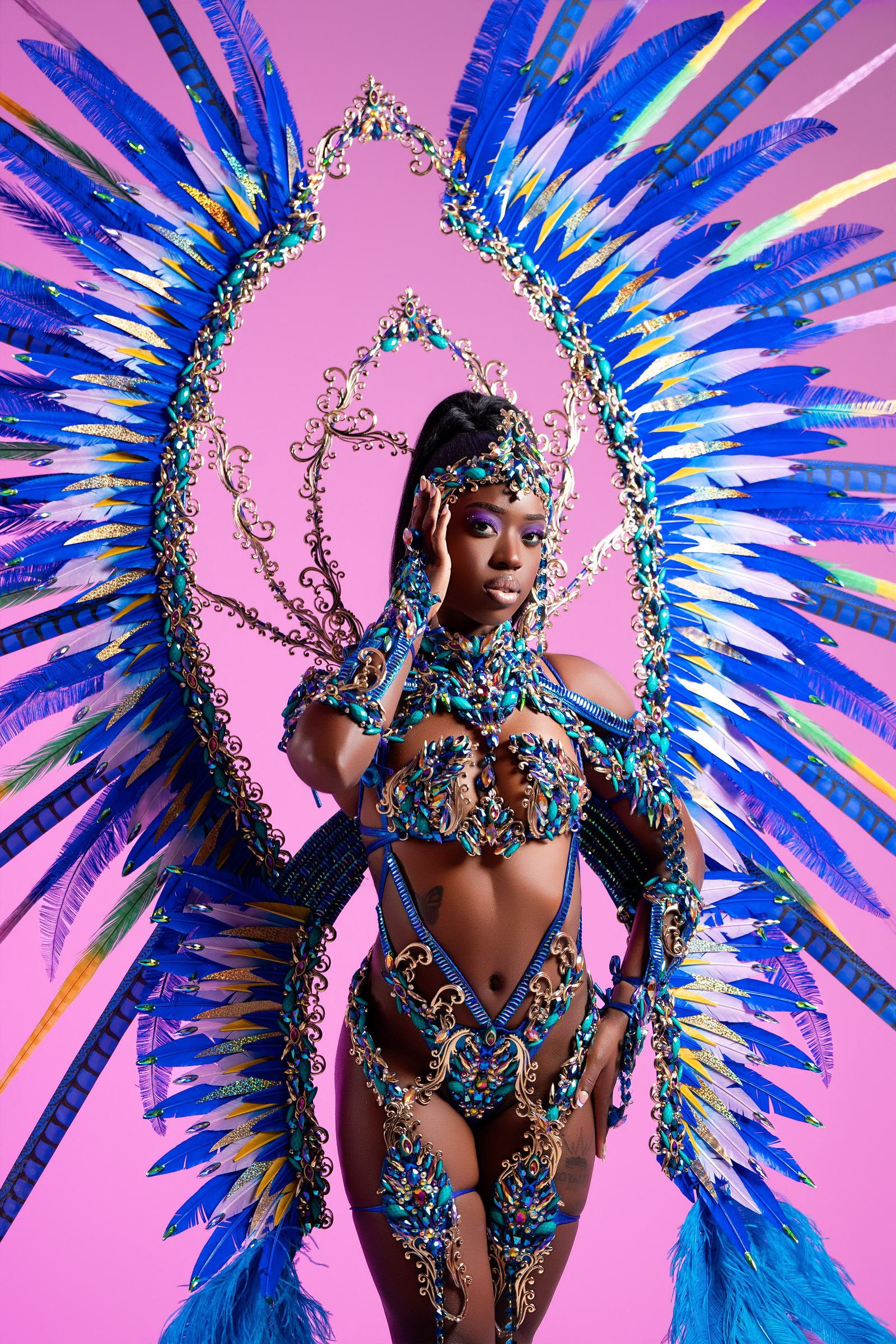 Carnival costume with a large blue and turquoise feather backpack on a pink background